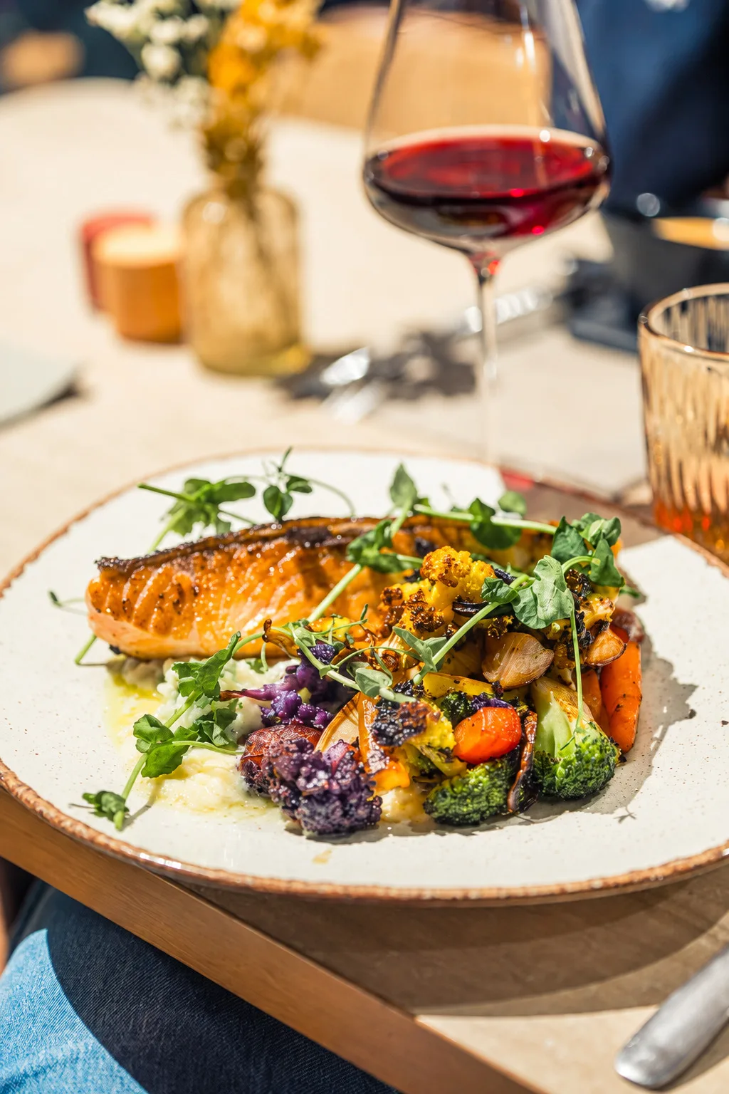 Assiette de saumon et légumes accompagnée d’un verre de vin au Bistro